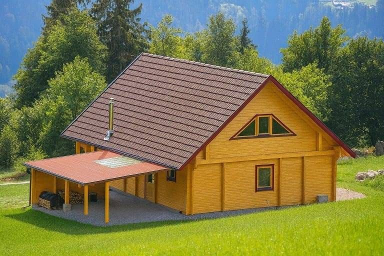 Ferienhaus Rügen: Gelbes Holzhaus mit braunem Dach und Carport auf grünem Rasen vor Bäumen.