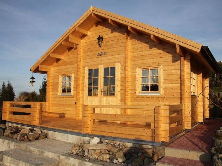 Blockhaus kaufen Blockhaus Bodensee: Gemütliches Holzhaus mit Terrasse und Fenstern unter blauem Himmel. Ideal für Urlaub und Entspannung.