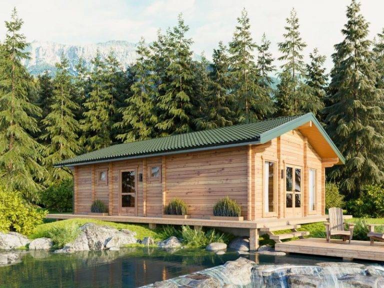 Blockhaus Brandenburg: Holzhaus mit grünen Dachziegeln am Seeufer, umgeben von Bäumen und Bergen.